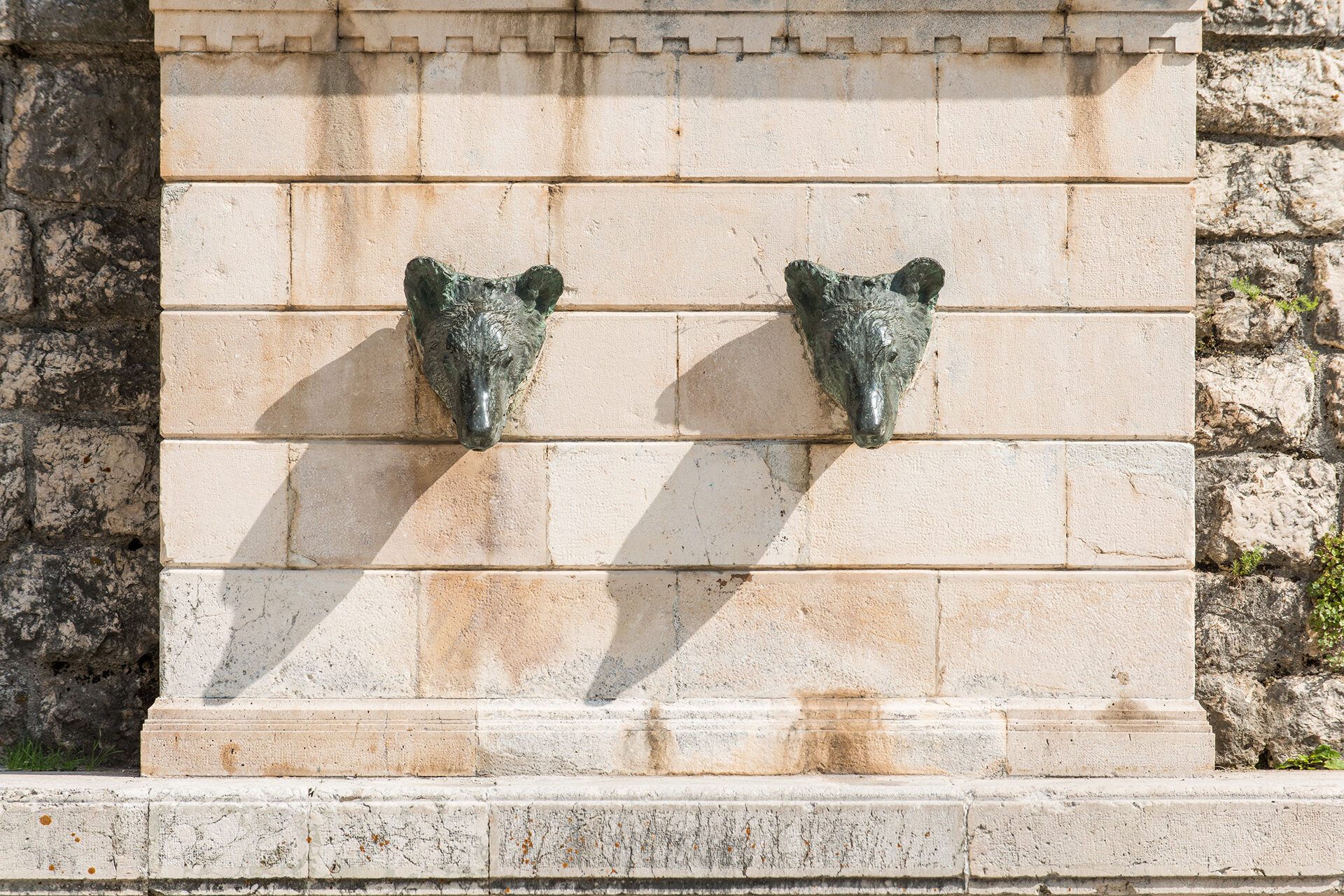 Close-up of the famous Bear Fountain in Pescasseroli, with two bronze bear heads mounted on a stone wall, a symbolic site linked to the PNALM. | © Umberto Esposito - Wildlife Adventures